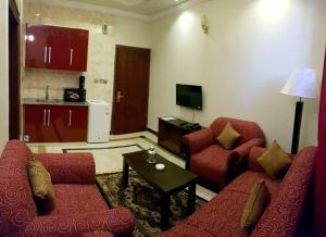 a living room with two red couches and a kitchen at Triple One Hotel Suites in Abbottabad