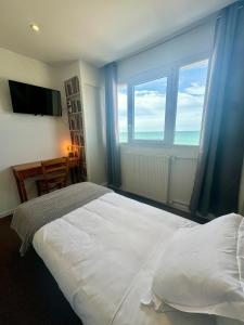 a bedroom with a large white bed and a large window at Le Clos Normand in Saint-Aubin-sur-Mer