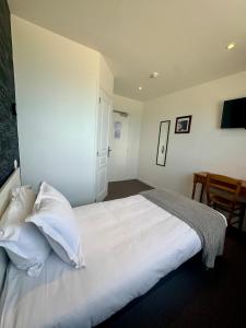 a bedroom with a bed with white sheets and pillows at Le Clos Normand in Saint-Aubin-sur-Mer
