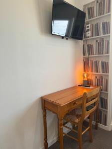 a wooden desk with a television on a wall at Le Clos Normand in Saint-Aubin-sur-Mer