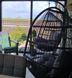 une cage pour oiseaux assise au-dessus d'une terrasse couverte dans l'établissement Vue unique sur le Mont St Michel, à Huisnes-sur-Mer