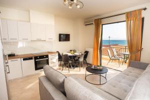 a living room with a couch and a kitchen with a table at Alkioni Suites , beachfront, with sea view in Kókkinos Pírgos