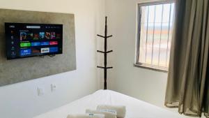 1 dormitorio con 1 cama y TV en la pared en Fortal Flat, en Fortaleza