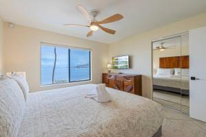 a bedroom with a bed with a ceiling fan and a window at Kihei Beach Resort 301- Oceanfront 2 bedroom 2bath condo on 6 mile beach in Kihei