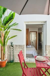 1 dormitorio y patio con mesa roja y sillas. en Studio Novena Little Apartments, en Cádiz