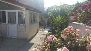 a garden with pink flowers and a house at Apartman Mir in Kaštela