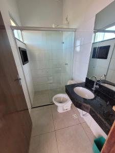 a bathroom with a toilet and a sink and a mirror at Quarto Solteiros Amigos - Queen's Hotel in Formosa