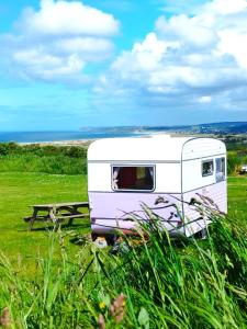 une caravane blanche garée dans un champ avec une table de pique-nique dans l'établissement Camping Les Ronds Duval face aux îles anglo-normandes, à Les Moitiers-dʼAllonne