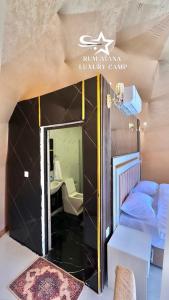 um pequeno quarto com uma cama e um espelho em RUM ATANA lUXURY CAMP em Wadi Rum