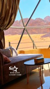 - un salon avec un canapé et une vue sur le désert dans l'établissement RUM ATANA lUXURY CAMP, à Wadi Rum