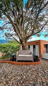 a couch sitting under a tree in front of a building at Finca acogedora en Villeta con piscina privada in Villeta