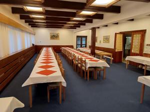 Hotel Bečva na Horní Bečvě في هورني بيسافا: صف من الطاولات في غرفة مع طاولات وكراسي بيضاء
