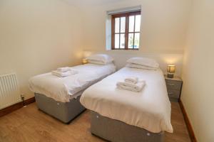 two beds in a room with towels on them at The Granary in Penzance