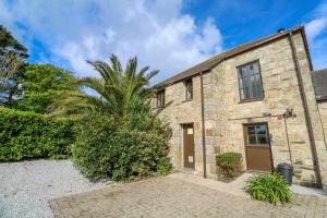an old stone house with a palm tree in front of it at The Granary in Penzance