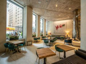 un restaurante con mesas, sillas y ventanas grandes en The Marmara Park Avenue, en Nueva York