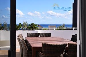 a wooden table and chairs on a balcony with the ocean at "5th Av" Sol del Caribe Apart Hotel in Playa del Carmen