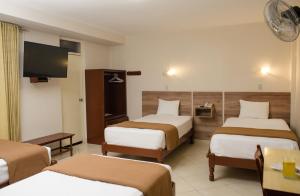 Habitación de hotel con 3 camas y TV de pantalla plana. en Hotel Santa Rosa, en Chiclayo