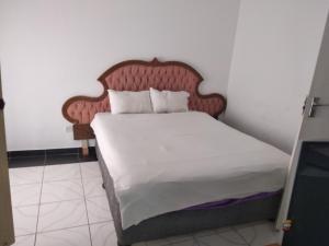 uma cama com uma cabeceira de madeira num quarto em Brackendene Lodge em Gaborone