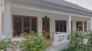 een wit huis met houten deuren en ramen bij Pai Family House in Pai