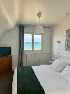 um quarto com uma cama e uma janela com o oceano em Le Clos Normand em Saint-Aubin-sur-Mer