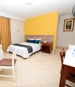ein Schlafzimmer mit einem Bett, einem Tisch und einem Stuhl in der Unterkunft Hotel Santa Rosa in Chiclayo