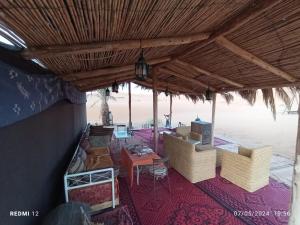 ein Wohnzimmer mit Stühlen, einem Tisch und Wasser in der Unterkunft Kasbah Mohayut in Merzouga
