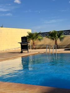 um piano sentado ao lado de uma piscina com palmeiras em Charmante villa avec piscine DAR LUD em Chichaoua