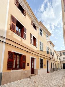 a building with brown shuttered windows on a street at Sant Cesc in Ciutadella