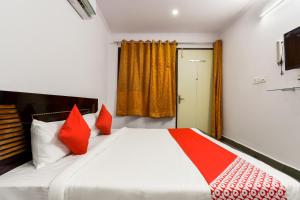 Schlafzimmer mit einem Bett mit roten Kissen und einem Fenster in der Unterkunft Flagship Sitar Guest House in Rudrapur