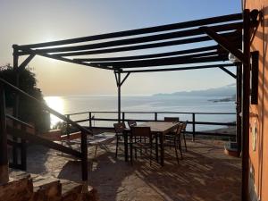 une terrasse avec une table et des chaises et l'océan dans l'établissement DOMO A MARE, à Magomadas