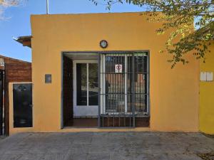 un bâtiment jaune avec une porte et un portail dans l'établissement Dpto BBB, à Zapala