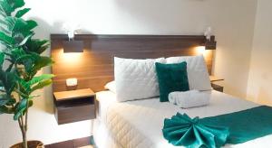 a bedroom with a large white bed with green pillows at Kali Hotel in Santa Ana