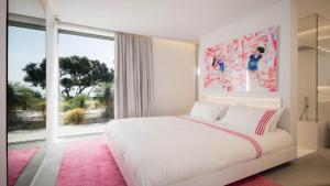 a bedroom with a white bed and a large window at Amamia in Saint-Tropez