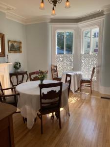 a dining room with a table and chairs and windows at The Red House Fredericton in Fredericton