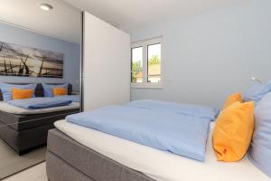 1 dormitorio con 2 camas con almohadas azules y naranjas en Residenz Blinkfueer Whg_ 6 _Poseid, en Rerik