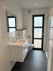 Baño blanco con lavabo y aseo en Marina Strandbad Chalet Aan het Strand mit Zaun Haus Nr 133, en Olburgen