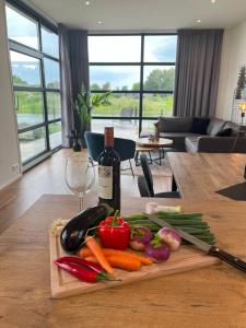 a cutting board with vegetables and a bottle of wine at Marina Strandbad Chalet Aan het Strand mit Zaun Haus Nr 133 in Olburgen