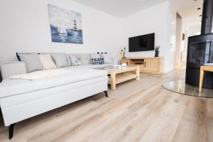 a living room with a white couch and a tv at Haus Q Superior - Hälfte 1 in Zingst