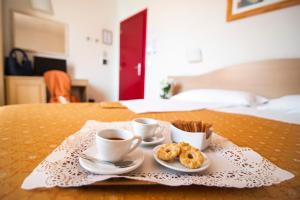 una mesa con dos tazas de café y pasteles. en Hotel La Colonna, en Siena