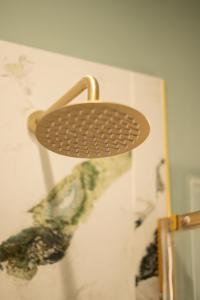 a metal strainer on the wall of a bathroom at L Suites The Writer's House in Gythio