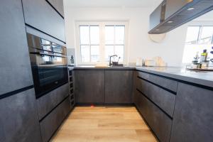 a kitchen with black cabinets and a sink at Haus Q Superior - Hälfte 2 in Zingst