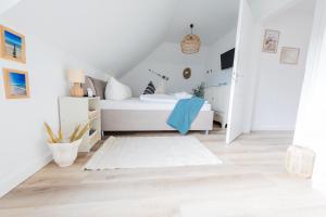 a bedroom with a white bed and a white rug at Haus Q Superior - Hälfte 2 in Zingst