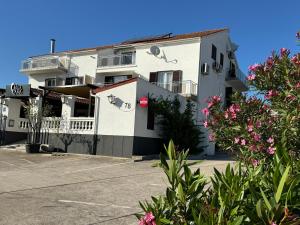 a white building with flowers in front of it at Hotel Restaurant Sjor Luka Turanj in Turanj