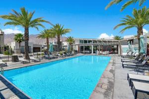a swimming pool with palm trees and chairs at The Luxe Vibe in Palm Springs