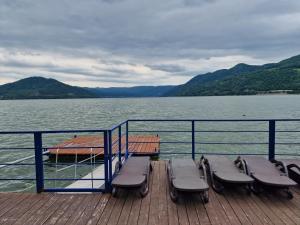 une jetée avec des chaises et un bateau sur l'eau dans l'établissement Casa Andrei, à Orşova