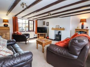 a living room with two leather couches and a tv at Rhodale Cottage in Barmston
