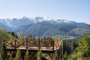 a wooden deck with mountains in the background at Hacienda Kościelisko - Kierpcówka 5 - Apartamenty z widokiem na Tatry & SPA in Kościelisko