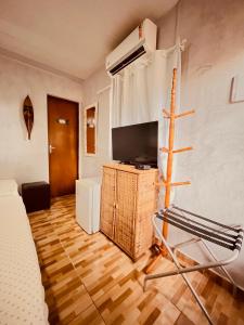 um quarto com uma cama, uma televisão e uma cadeira em Martinelli Residence em Fernando de Noronha