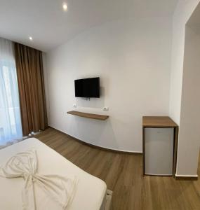 1 dormitorio con 1 cama y TV en la pared en Vila Beqja en Durrës
