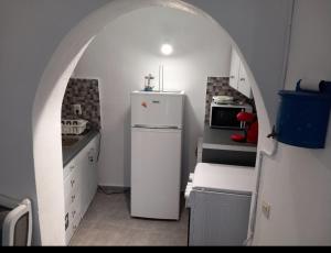 a small kitchen with a white refrigerator and an archway at VI STA FINIKIAS VILLA in Oia